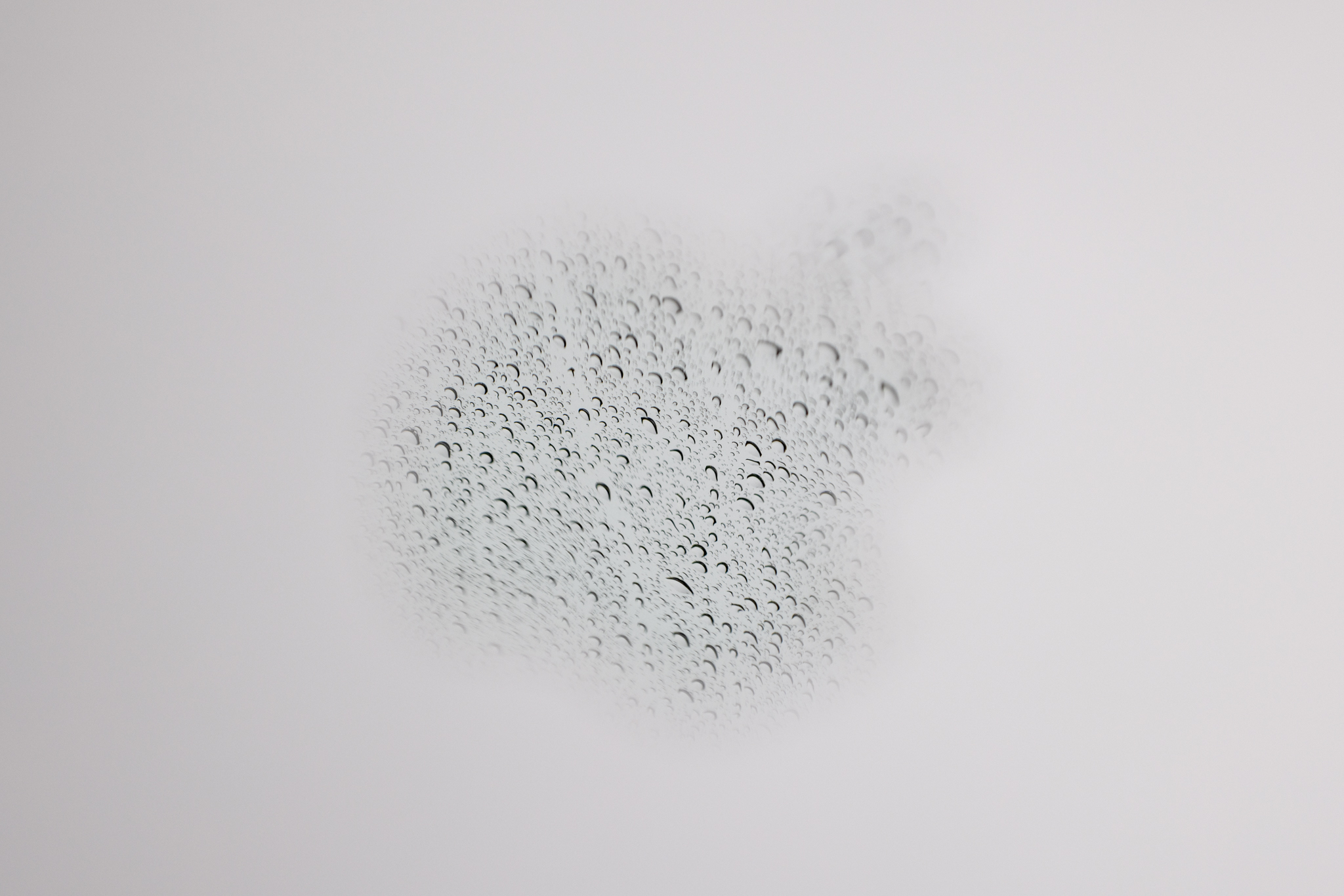 A reflection of rain in the Apple logo on a laptop photographed at f/8